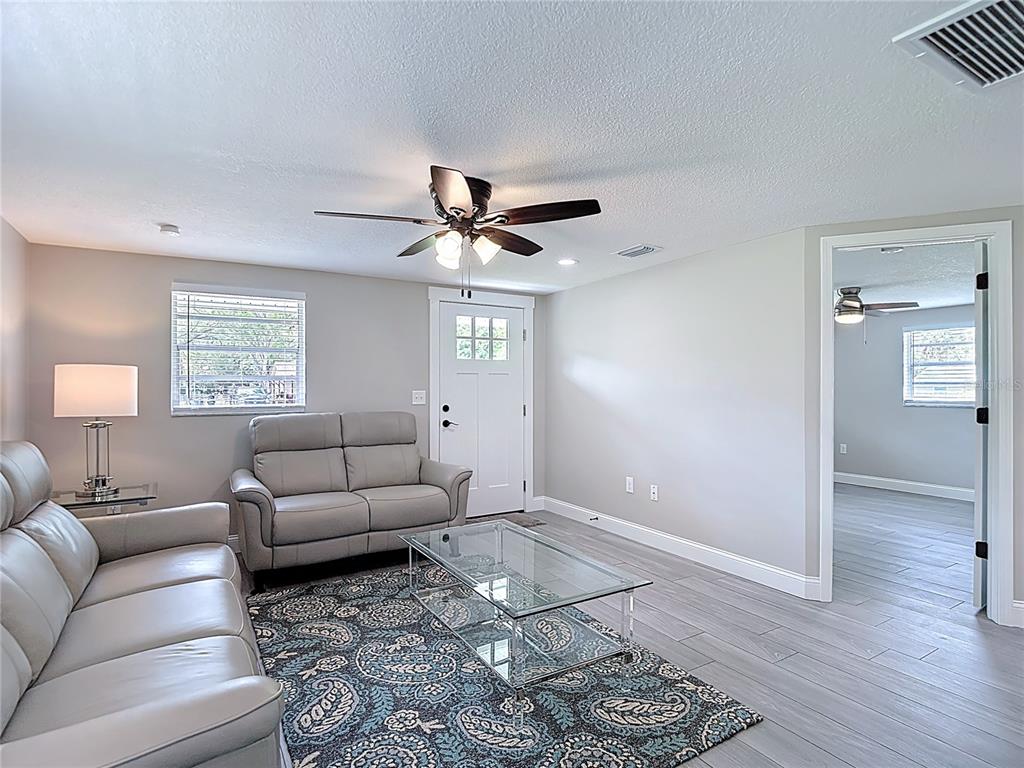 A living room features gray leather sofas, a glass coffee table, and light-colored tile flooring — 14306 GUAVA STREET, HUDSON, FL