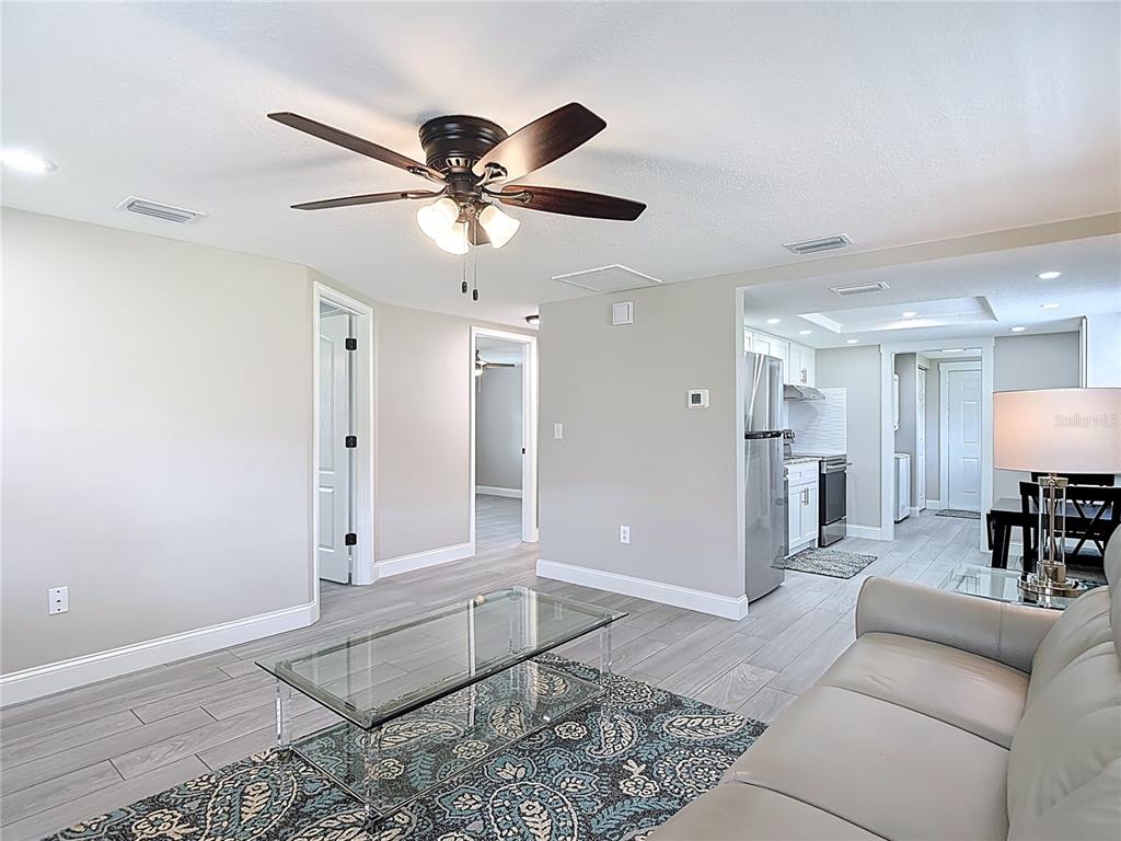 A living room with light gray tile floors, a glass coffee table, and a ceiling fan — 14306 GUAVA STREET, HUDSON, FL