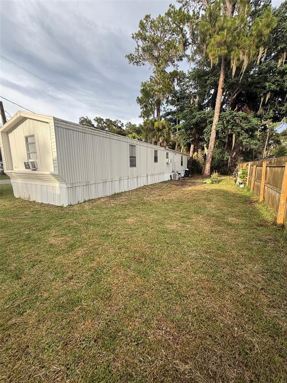 A white mobile home sits on a grassy lot next to a wooden fence — 35 SUNSET CIRCLE, LAKE ALFRED, FL