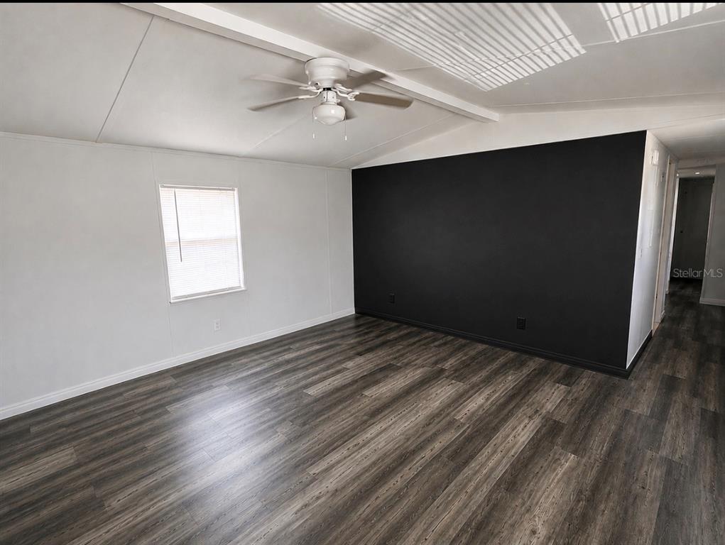 An empty room features gray wood-look flooring, white walls, and a black accent wall — 35 SUNSET CIRCLE, LAKE ALFRED, FL