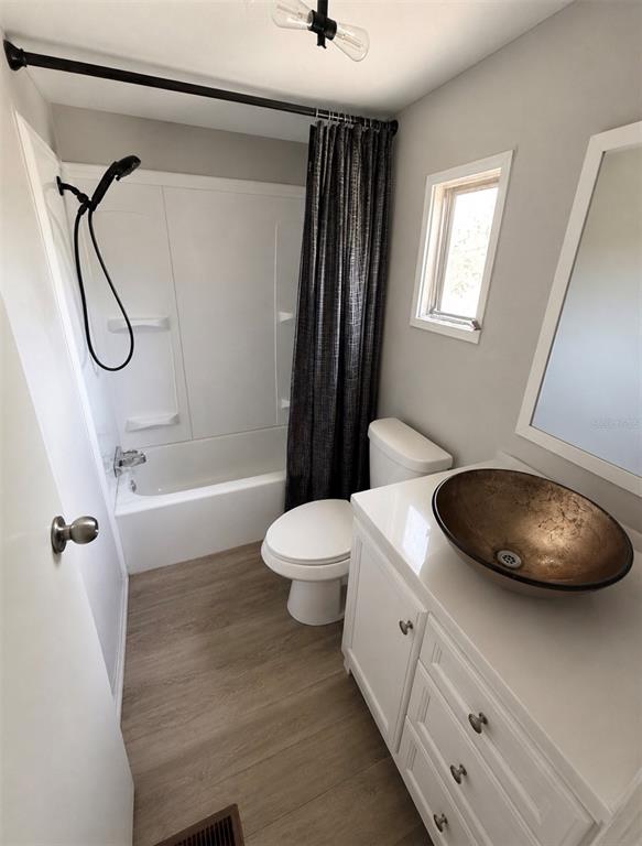 A bathroom features a white vanity with a bronze vessel sink, toilet, and shower-tub combo — 35 SUNSET CIRCLE, LAKE ALFRED, FL