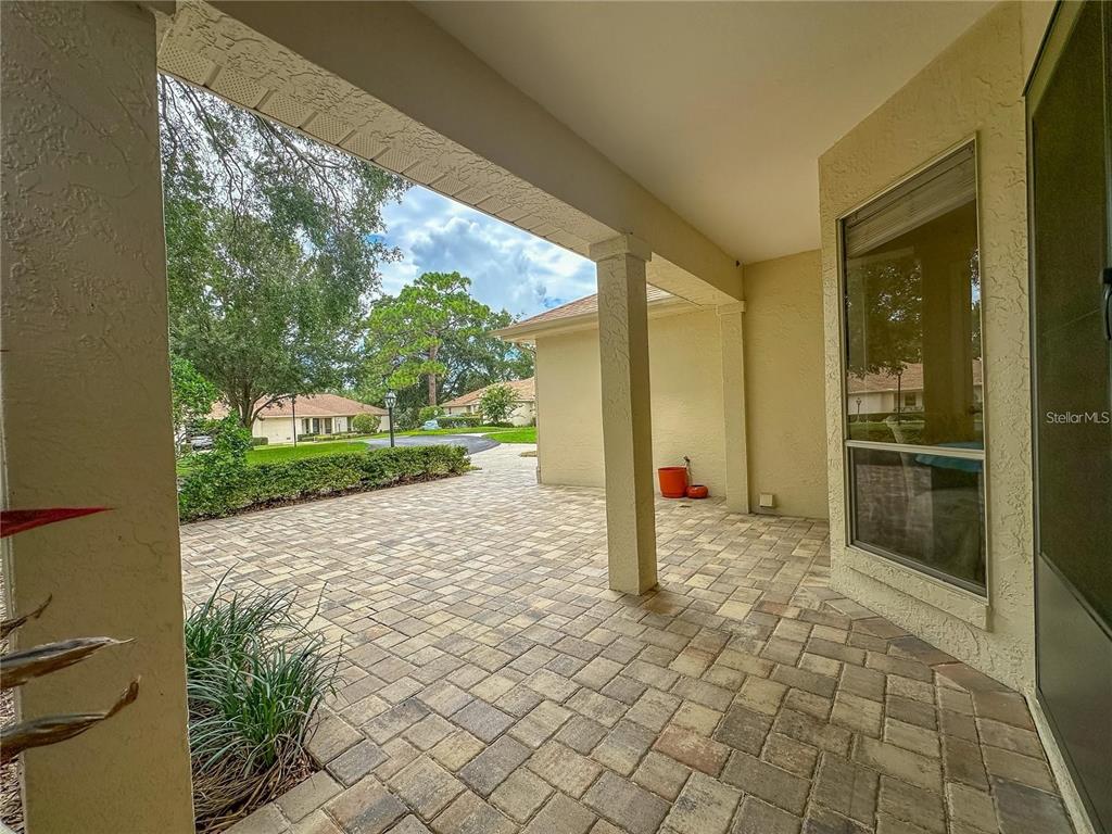 A covered patio features paver flooring, a support column, and a view of the neighborhood — 5941 W DEDHAM TRAIL, CRYSTAL RIVER, FL