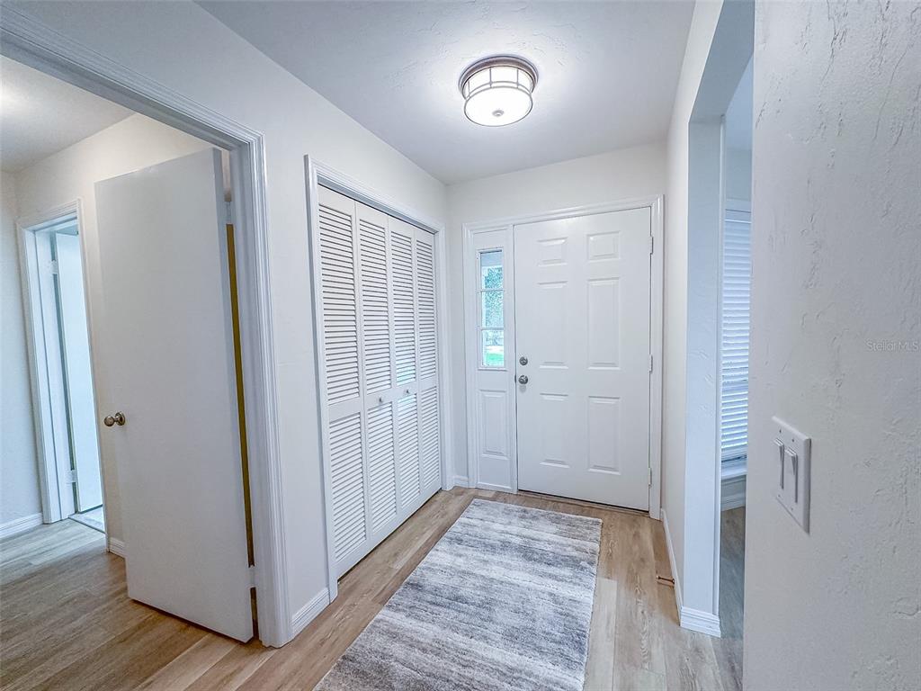 A bright entryway features a white front door, louvered closet doors, and light wood flooring — 5941 W DEDHAM TRAIL, CRYSTAL RIVER, FL