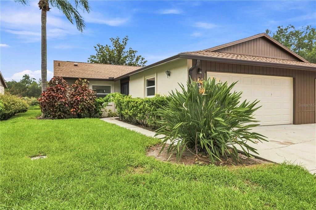 A single-story house with a beige exterior, a two-car garage, and a landscaped front yard — 4756 OAK HILL DRIVE UNIT 16, SARASOTA, FL