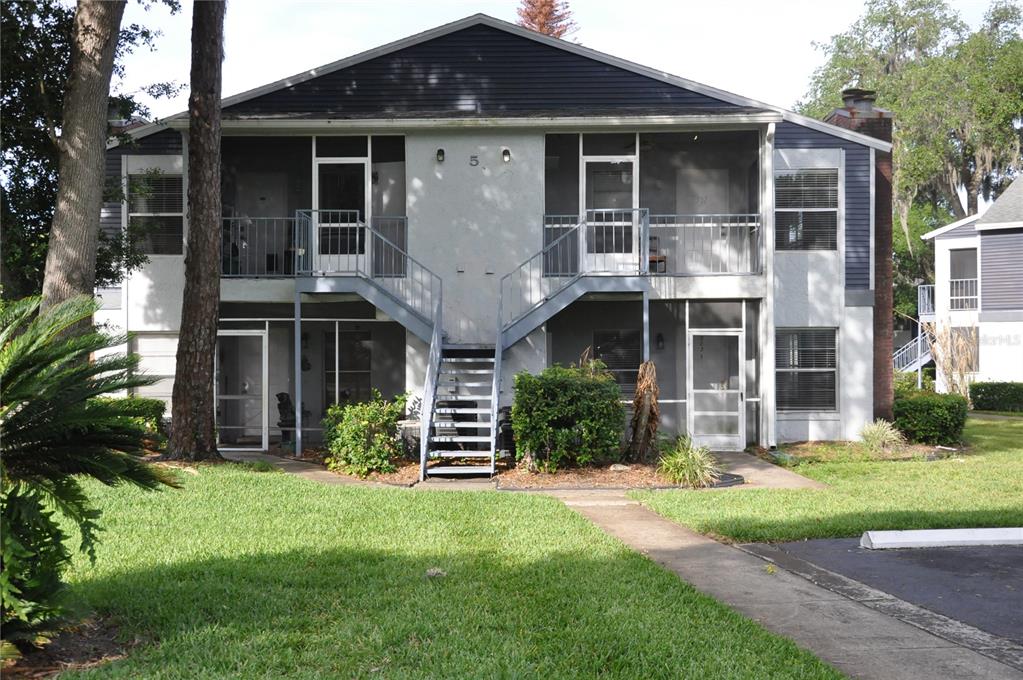 A two-story apartment building features a central staircase leading to upper-level screened balconies — 507 NORTHLAKE DRIVE UNIT 507, SANFORD, FL