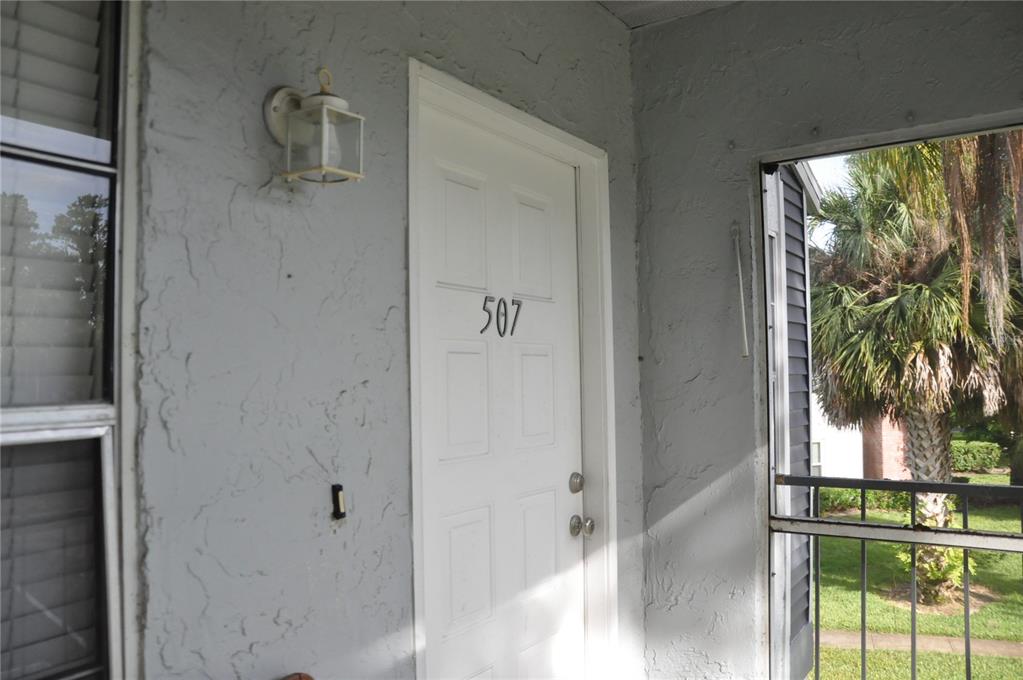 A white door with the number 507 is set in a gray stucco exterior wall — 507 NORTHLAKE DRIVE UNIT 507, SANFORD, FL