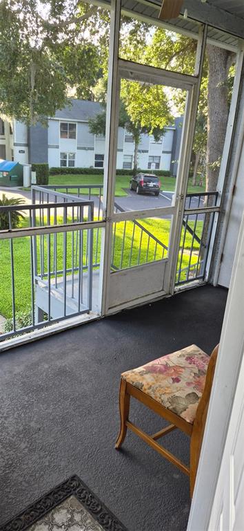 A screened-in balcony features a wooden chair with a floral cushion and a metal railing — 507 NORTHLAKE DRIVE UNIT 507, SANFORD, FL