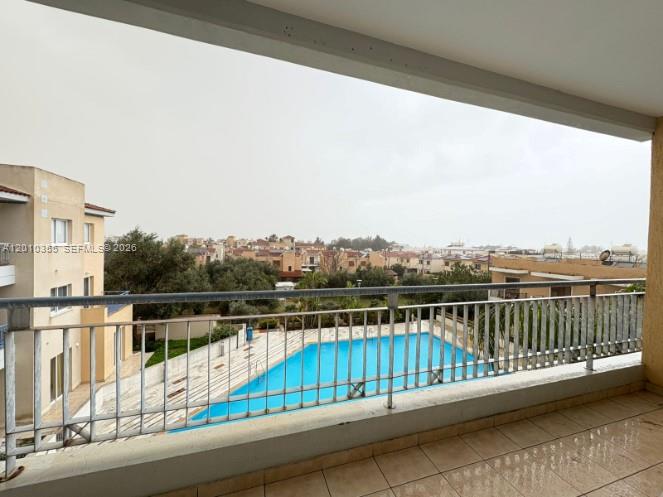 A balcony overlooks a swimming pool and a residential neighborhood under a cloudy sky — 27 Nicolaou Thiseos Str # 203, 8048, FL