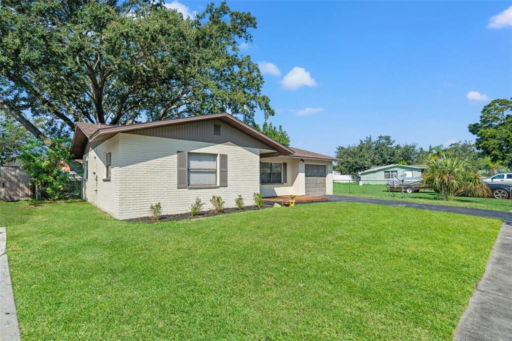 A single-story house with a white brick exterior, brown trim, and a front lawn — 5828 MARIPOSA DRIVE, HOLIDAY, FL