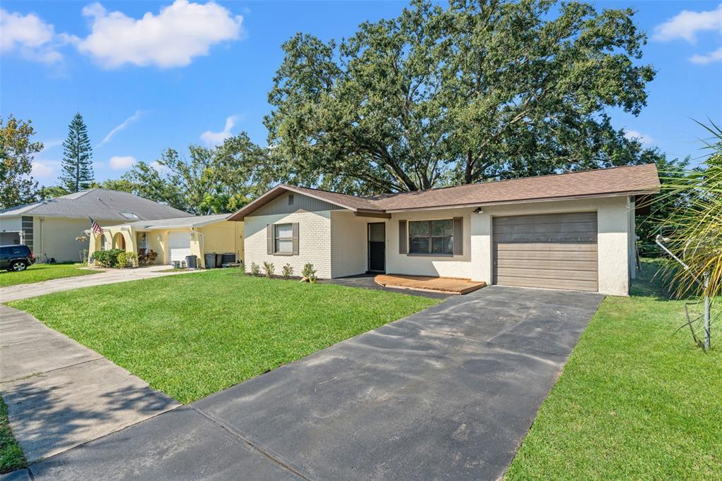 A single-story house with a brick facade, a brown roof, and an attached garage — 5828 MARIPOSA DRIVE, HOLIDAY, FL