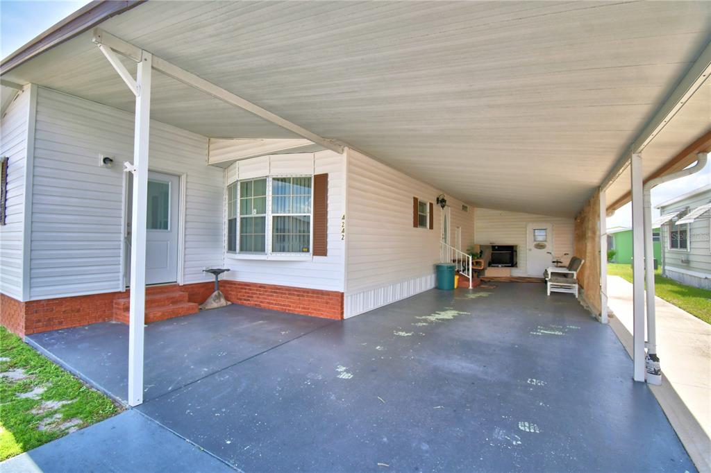 A white mobile home with a large carport, brick skirting, and a bay window — 4242 CEDARWOOD STREET, WINTER HAVEN, FL