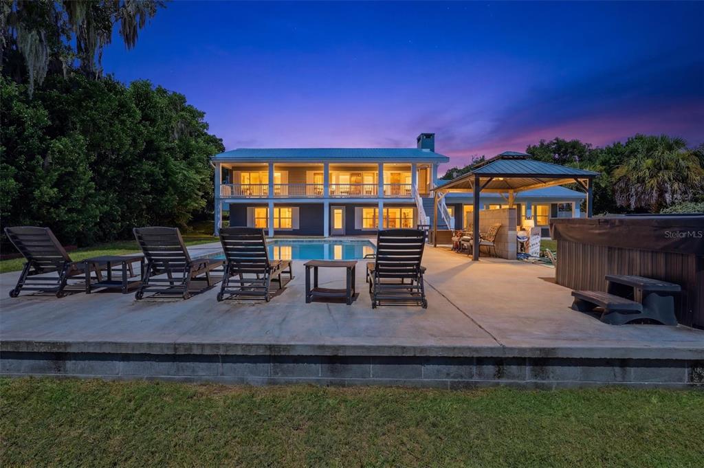 A two-story house with a pool, patio, hot tub, and gazebo at twilight — 8085 NE 310TH AVENUE, FORT MC COY, FL