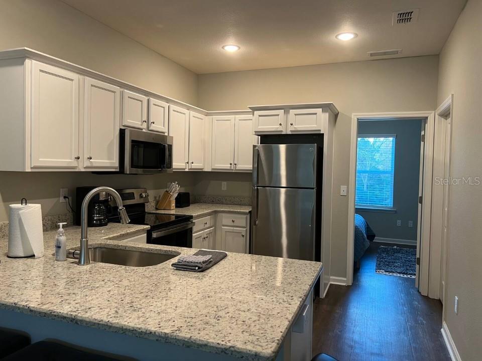 A kitchen with white cabinets, granite countertops, stainless steel appliances, and an island sink — 2288 DEL CARMEL WAY UNIT 14, TALLAHASSEE, FL