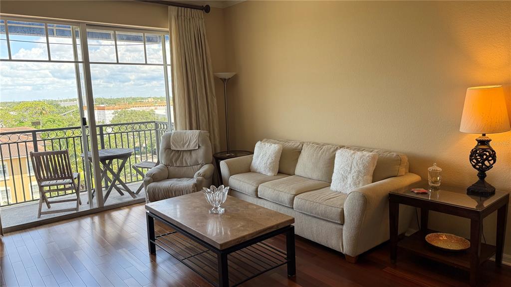 A living room with a beige sofa, coffee table, recliner, and a balcony with outdoor seating — 1064 N TAMIAMI TRAIL UNIT 1635, SARASOTA, FL