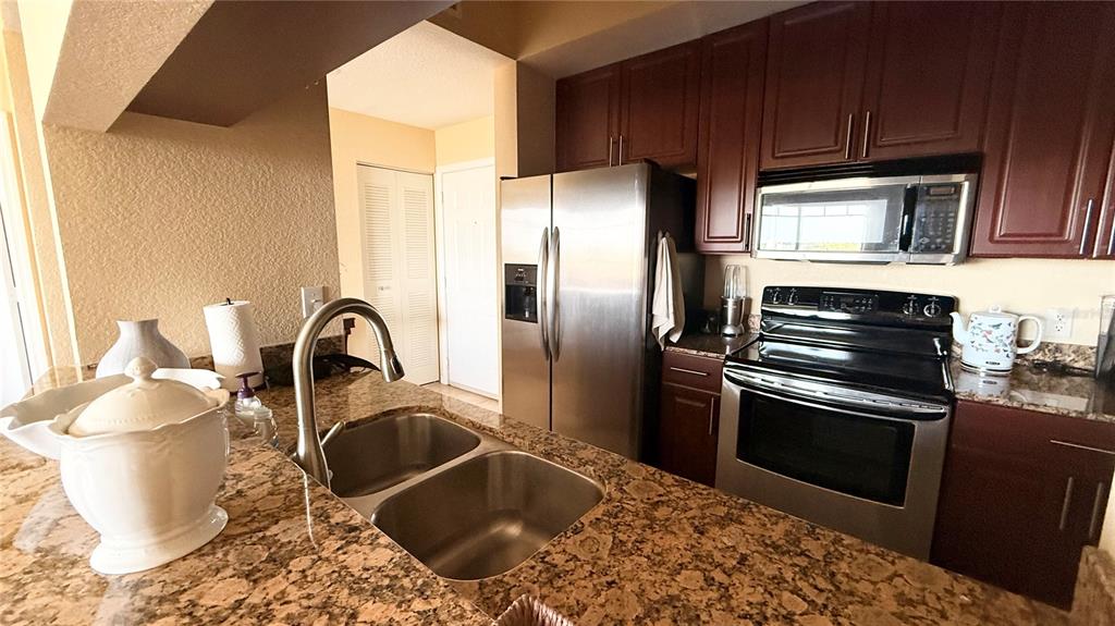 A kitchen features dark wood cabinets, stainless steel appliances, and brown granite countertops — 1064 N TAMIAMI TRAIL UNIT 1635, SARASOTA, FL
