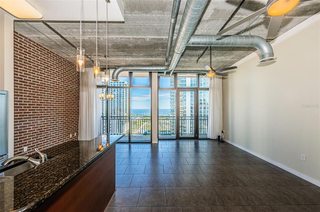 An open-concept living area features a brick wall, industrial exposed ductwork, and floor-to-ceiling windows — 175 2ND STREET S UNIT P04, ST PETERSBURG, FL
