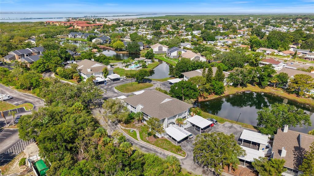 An aerial view shows a multi-story apartment complex surrounded by trees, ponds, and parking areas — 8350 SAVANNAH TRACE CIRCLE UNIT 1703, TAMPA, FL