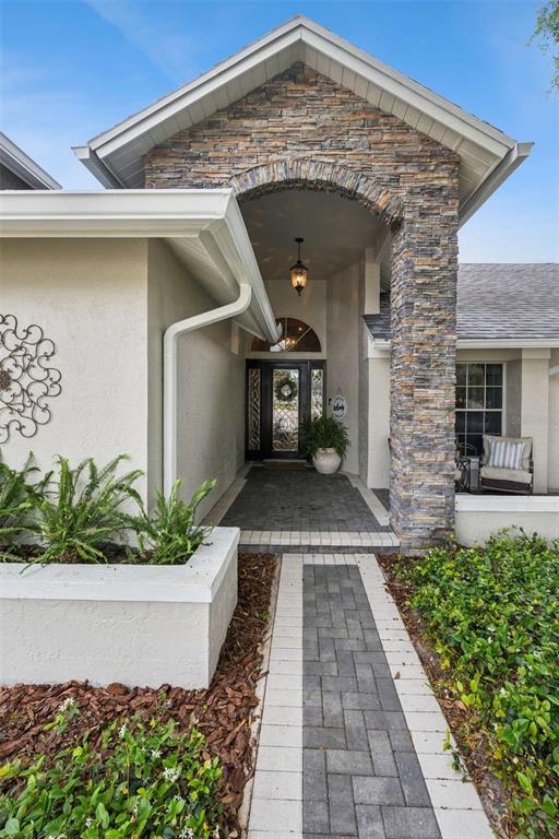 The exterior of a house features a stone-accented entryway, a paved walkway, and a planter box — 4571 KAWILLA CREST PLACE, WINTER PARK, FL