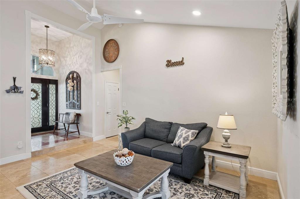 A living room features a grey loveseat, a wooden coffee table, and a vaulted ceiling — 4571 KAWILLA CREST PLACE, WINTER PARK, FL