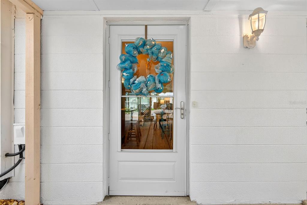 A white exterior door with a blue mesh wreath is centered on a white wall — 5055 LIVE OAK CIRCLE UNIT 5055, BRADENTON, FL
