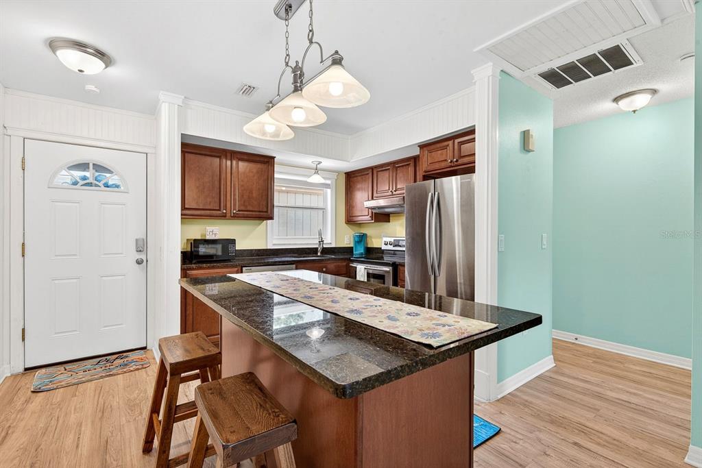 A kitchen features a dark granite island, wooden cabinets, stainless steel appliances, and light flooring — 5055 LIVE OAK CIRCLE UNIT 5055, BRADENTON, FL