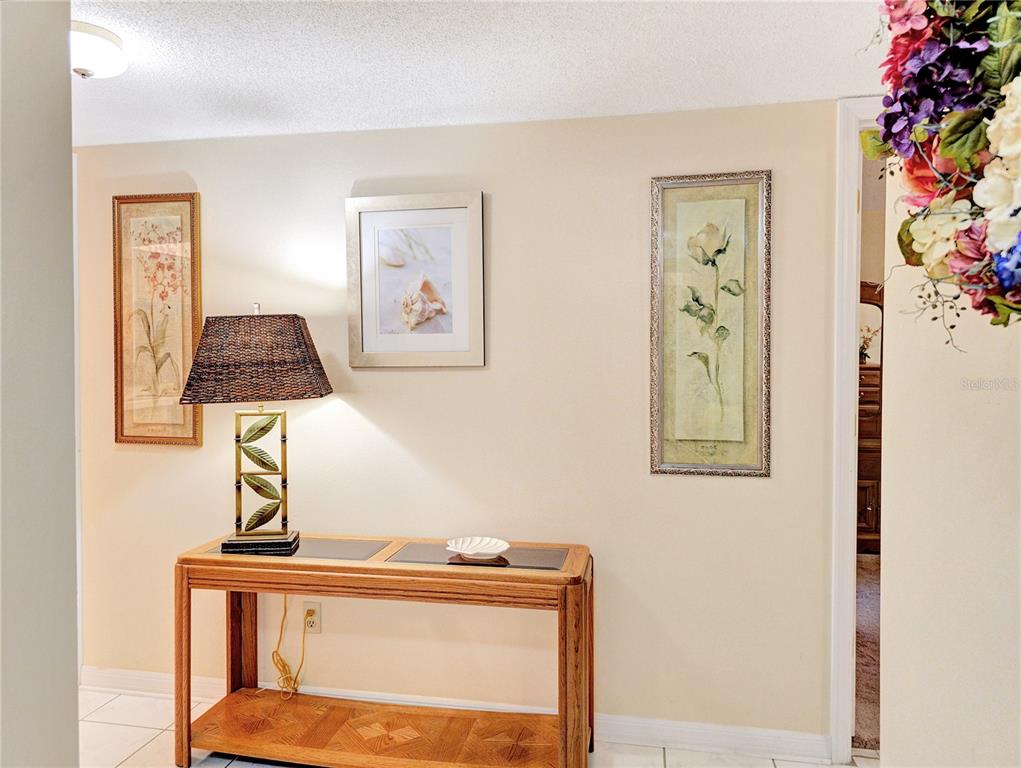 A hallway features a wooden console table with a lamp and three framed wall pictures — 700 MIDWAY DRIVE UNIT B, OCALA, FL
