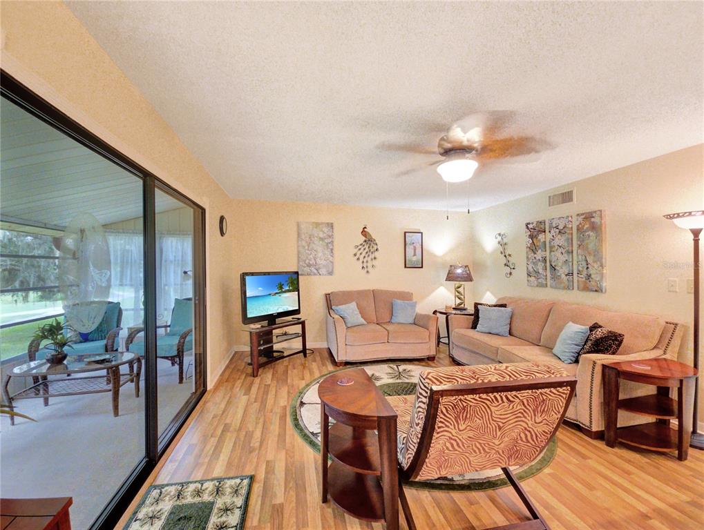 A living room features wood-look flooring, a ceiling fan, and a sliding glass door — 700 MIDWAY DRIVE UNIT B, OCALA, FL