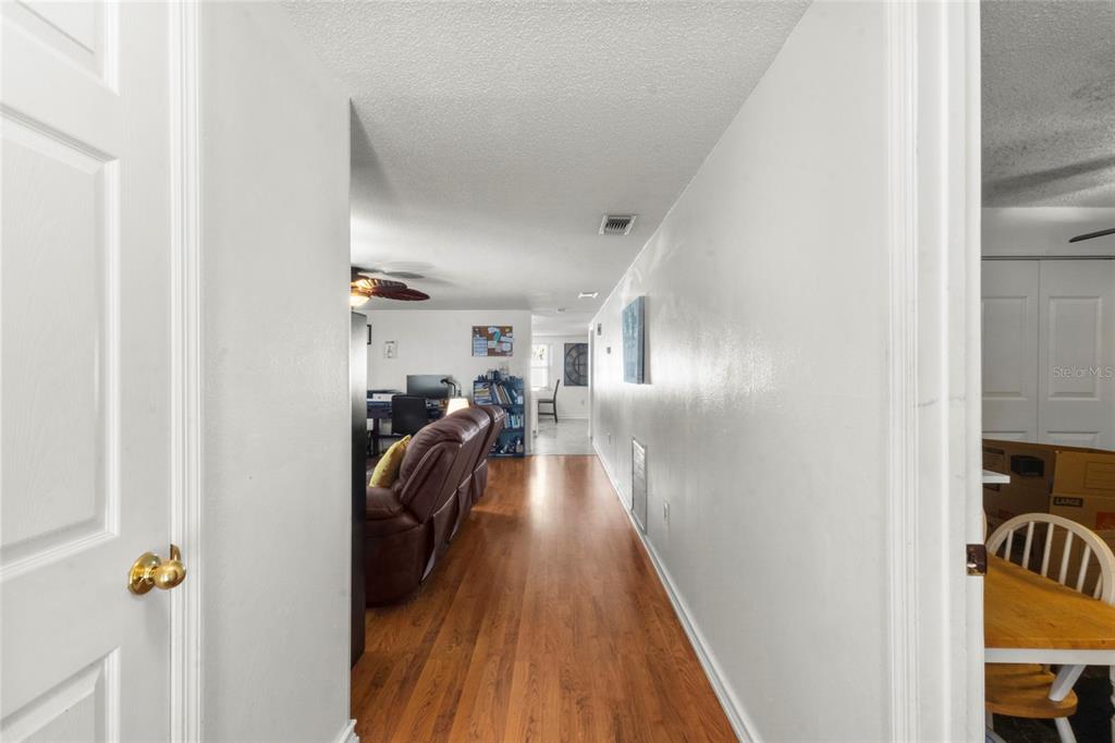 A hallway with wood-look flooring leads from a doorway into a living area — 3340 SUNSET BEACH DRIVE, VENICE, FL