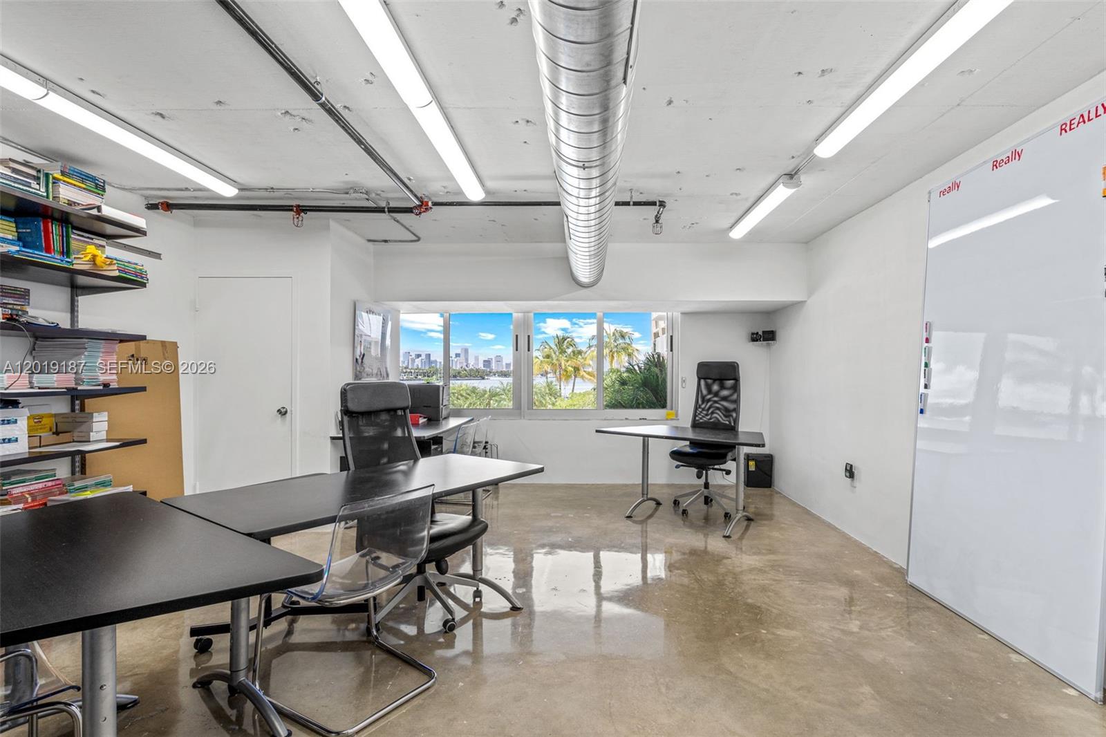 An office space features concrete floors, exposed ceiling ductwork, desks, and a large whiteboard — 1200 West Ave # 216, Miami Beach FL 33139, MIAMI BEACH, FL