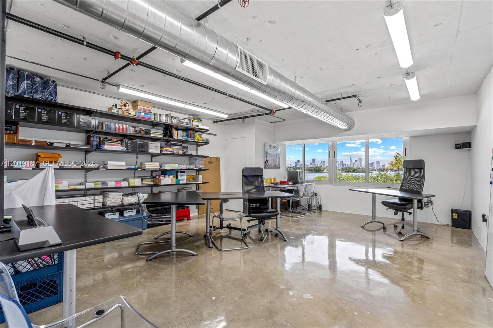 An office space features industrial ceilings, concrete floors, shelving units, and a city skyline view — 1200 West Ave # 216, Miami Beach FL 33139, MIAMI BEACH, FL