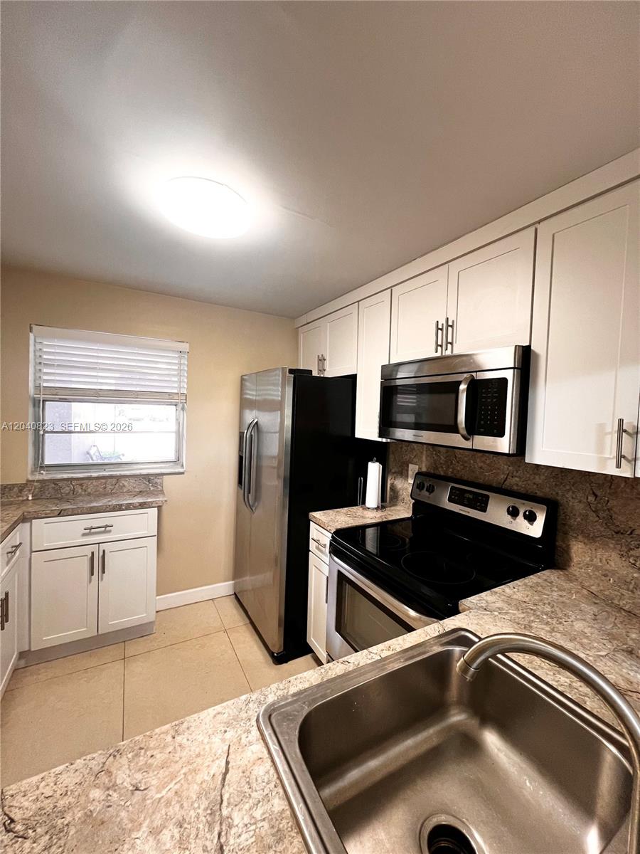 A kitchen features white cabinets, stainless steel appliances, and tan granite countertops — 9235 Lagoon Pl # 109, Davie FL 33324, DAVIE, FL