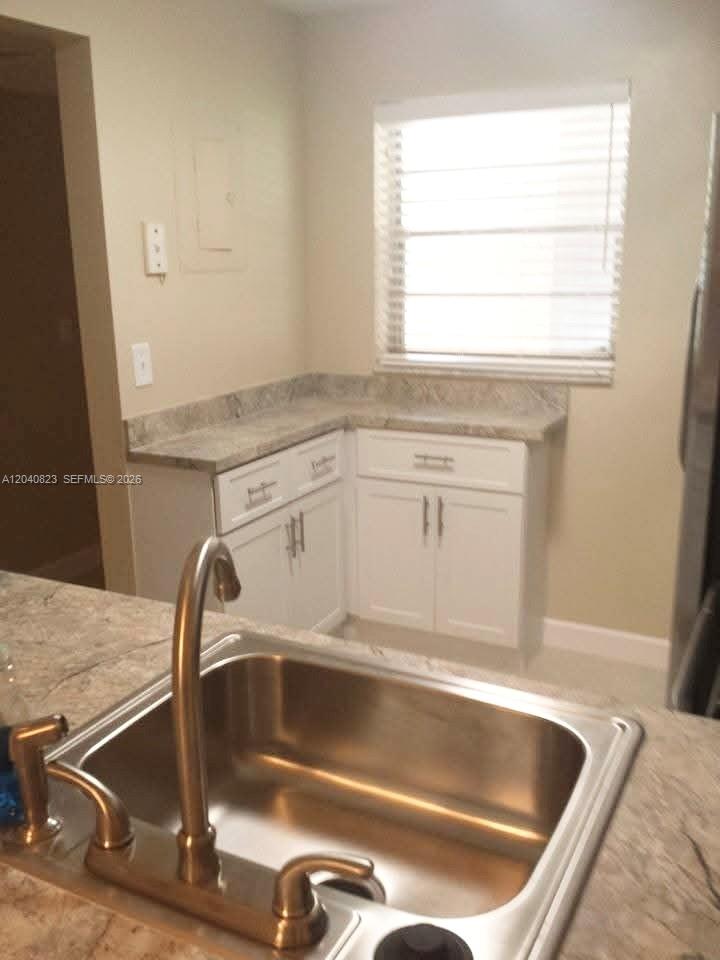 A kitchen features white cabinets, stone countertops, a stainless steel sink, and a window — 9235 Lagoon Pl # 109, Davie FL 33324, DAVIE, FL