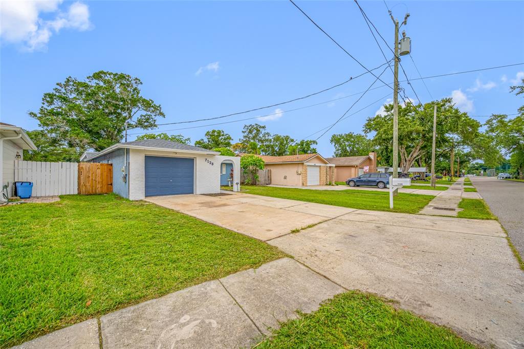 A single-story house with a blue garage door and a concrete driveway on a sunny day — 7128 64TH WAY N, PINELLAS PARK, FL