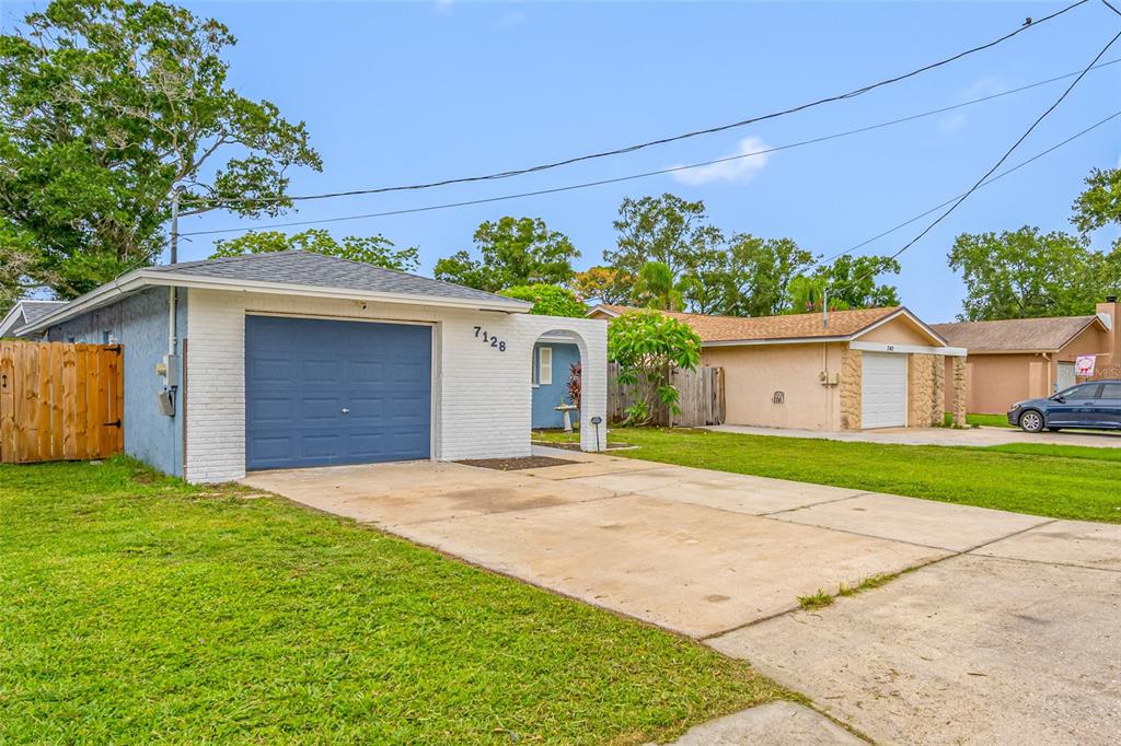 A single-story house with a blue garage door, white brick facade, and a concrete driveway — 7128 64TH WAY N, PINELLAS PARK, FL