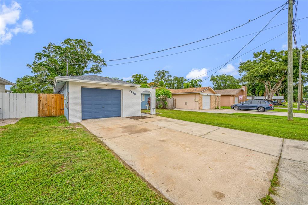 A single-story house with a blue garage door, white brick exterior, and a concrete driveway — 7128 64TH WAY N, PINELLAS PARK, FL