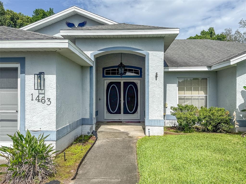 The exterior of a house features a concrete walkway leading to a double front door — 1463 BRIGADIER DRIVE, SPRING HILL, FL