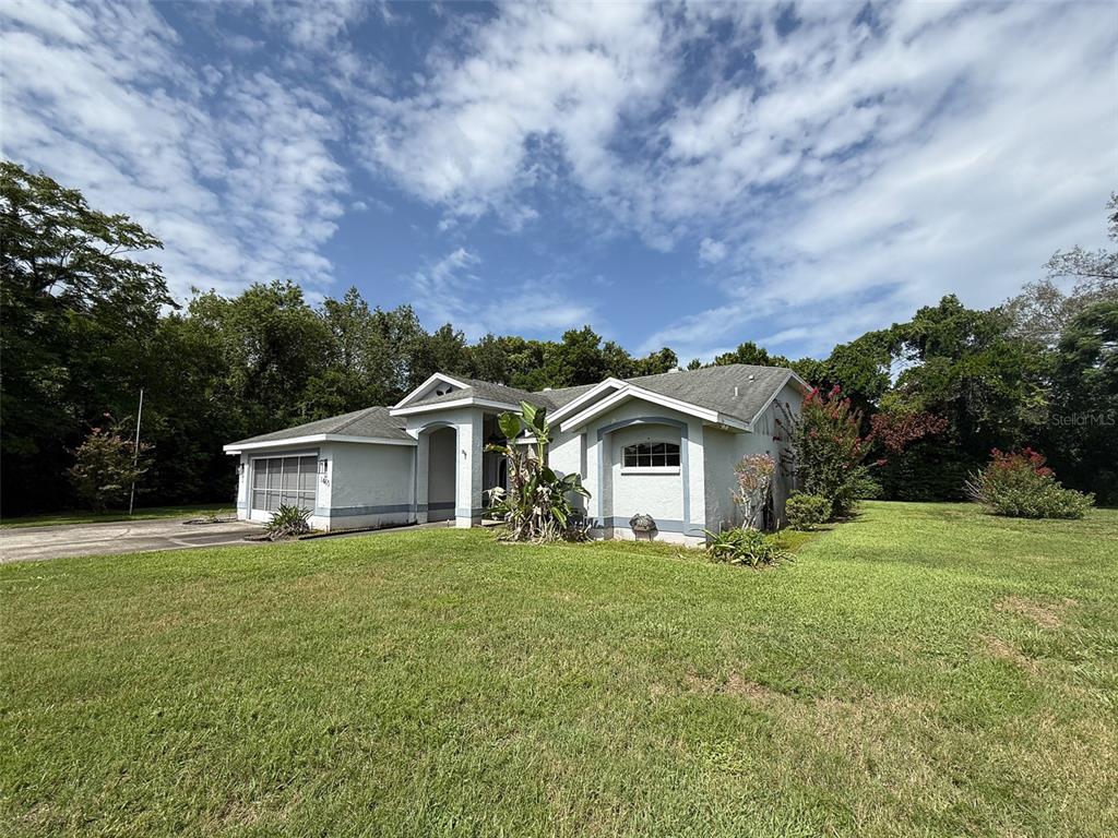 A single-story house with a light-colored stucco exterior, a garage, and a large front lawn — 1463 BRIGADIER DRIVE, SPRING HILL, FL