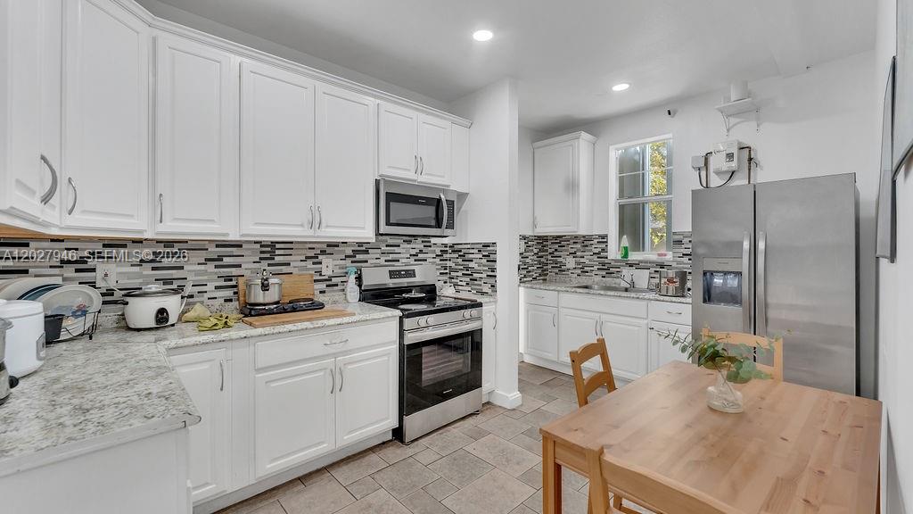 A kitchen features white cabinets, granite countertops, stainless steel appliances, and a wooden dining table — 242 SW 15th Ave, Miami FL 33135, MIAMI, FL