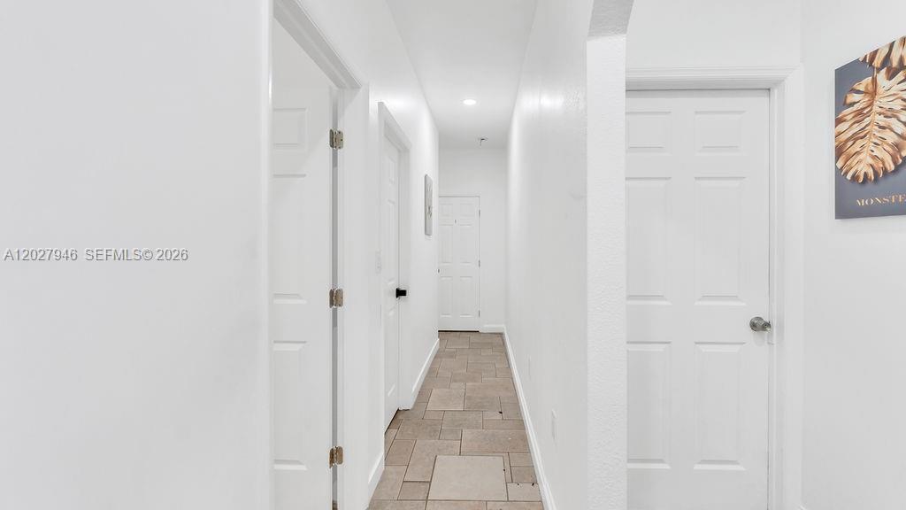 A narrow hallway features white walls, multiple closed doors, and light-colored tile flooring — 242 SW 15th Ave, Miami FL 33135, MIAMI, FL