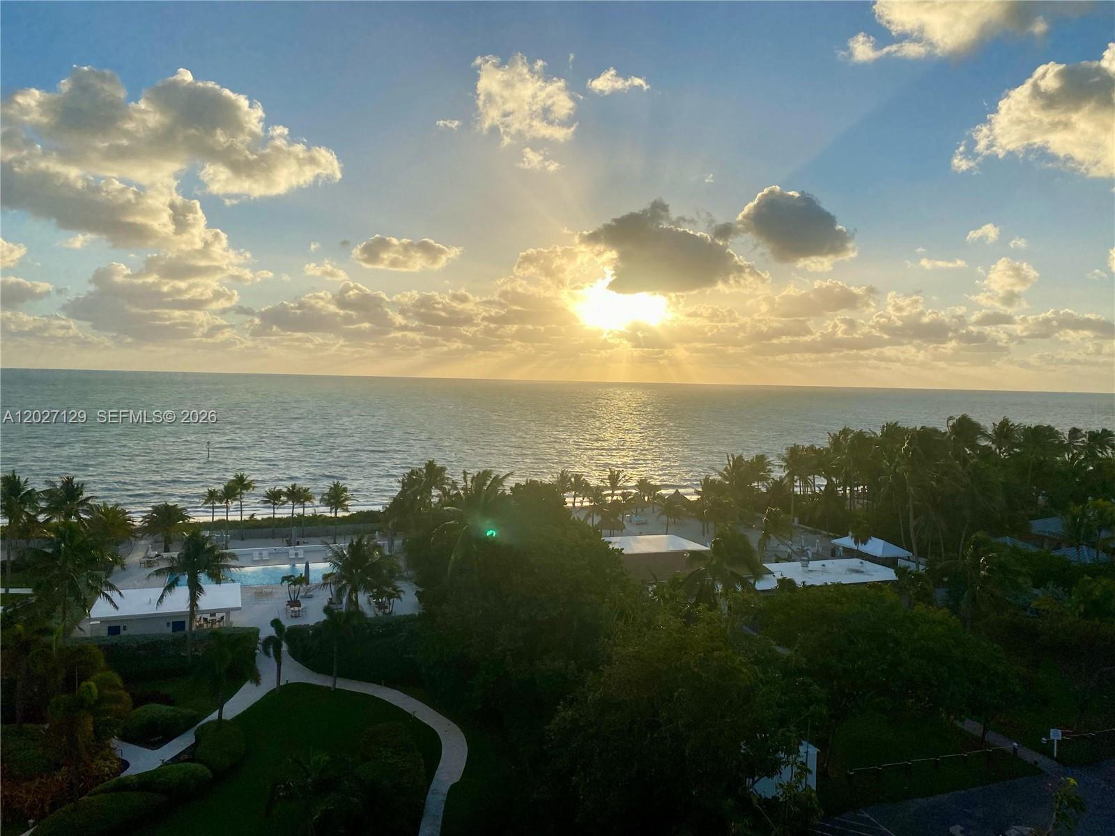 An elevated view of a tropical resort with a swimming pool overlooking the ocean — 607 Ocean Dr # 9K, Key Biscayne FL 33149, KEY BISCAYNE, FL