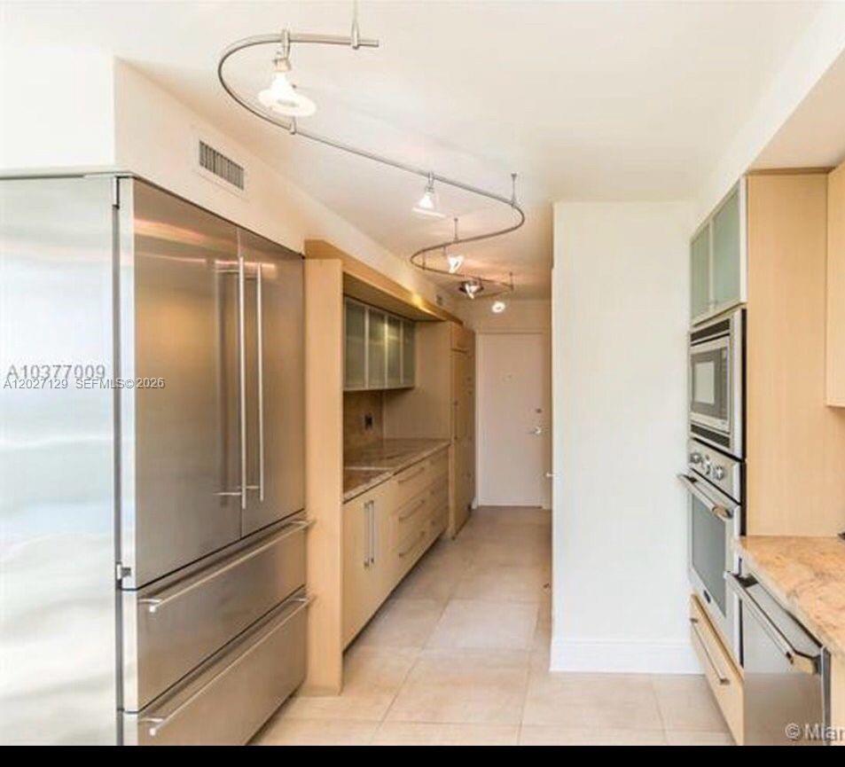 A galley-style kitchen features stainless steel appliances, light wood cabinetry, and track lighting — 607 Ocean Dr # 9K, Key Biscayne FL 33149, KEY BISCAYNE, FL