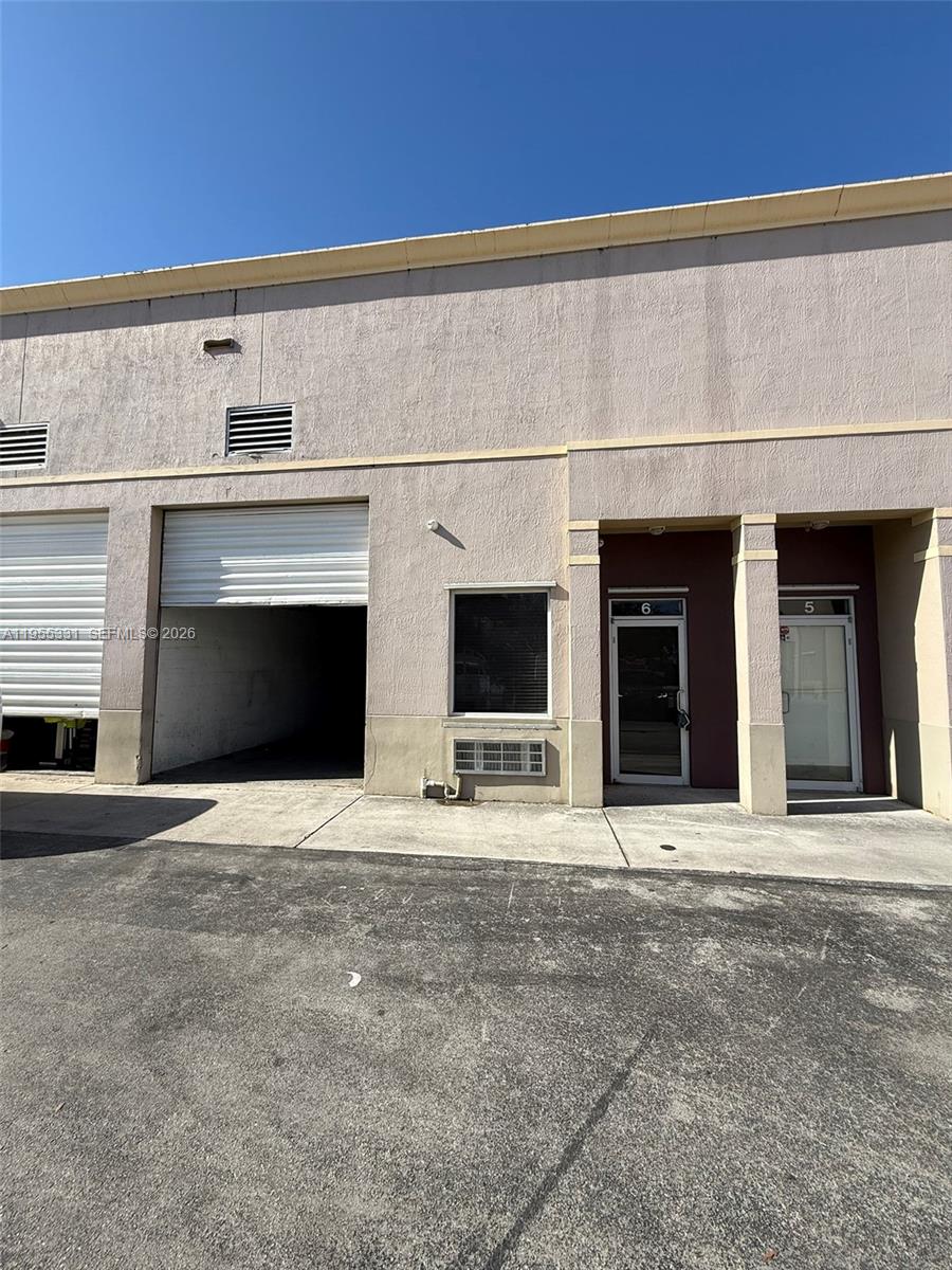 The exterior of a commercial building features two glass doors, a roll-up bay door, and windows — 15075 SW 137th St # 6, Miami FL 33196, MIAMI, FL