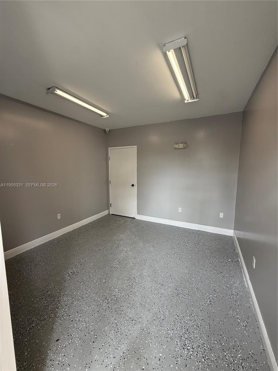 A room with gray walls, a speckled epoxy floor, and two overhead fluorescent light fixtures — 15075 SW 137th St # 6, Miami FL 33196, MIAMI, FL
