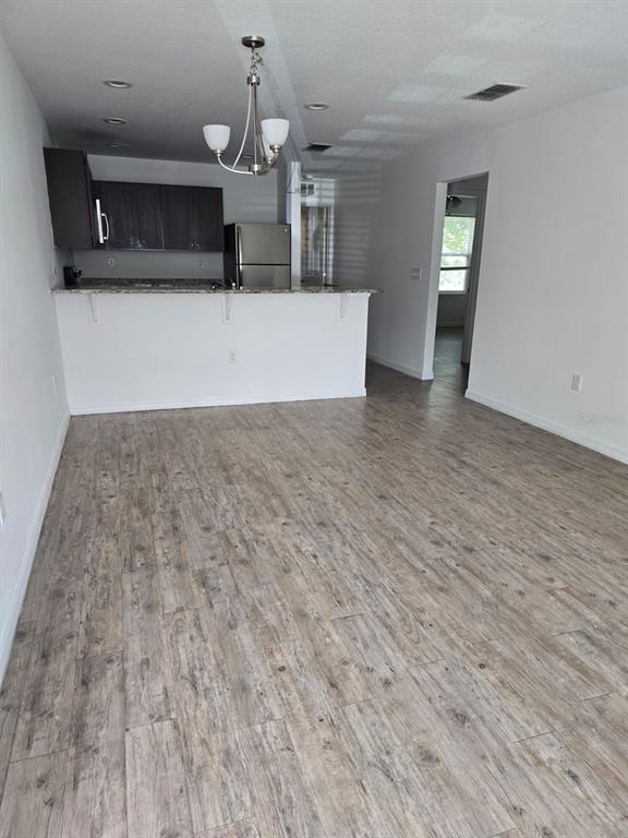 An open-concept living area features wood-look tile flooring, a breakfast bar, and dark kitchen cabinetry — 168 BOWIE LANE UNIT 101, KISSIMMEE, FL
