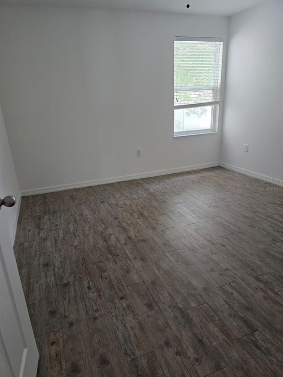 An empty bedroom features white walls, a single window with blinds, and wood-look flooring — 168 BOWIE LANE UNIT 101, KISSIMMEE, FL