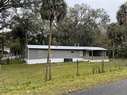 A single-story manufactured home with grey siding and a covered porch sits on a grassy lot — 7032 SE 170TH AVENUE ROAD, OCKLAWAHA, FL