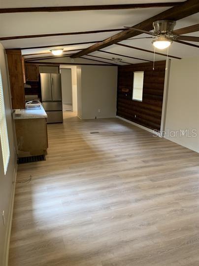 A room with light wood-look flooring, a ceiling fan, and a wood-paneled accent wall — 7032 SE 170TH AVENUE ROAD, OCKLAWAHA, FL