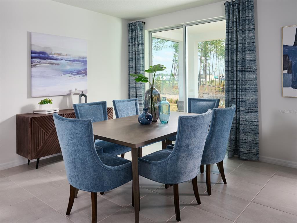 A dining room features a wooden table, six blue upholstered chairs, and sliding glass doors — 2057 ROSEWOOD DRIVE, BARTOW, FL