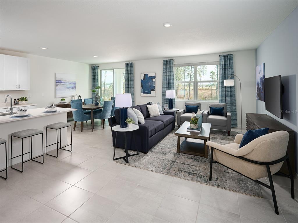 This open-concept living and dining area features a kitchen island, tile flooring, and blue accents — 2057 ROSEWOOD DRIVE, BARTOW, FL