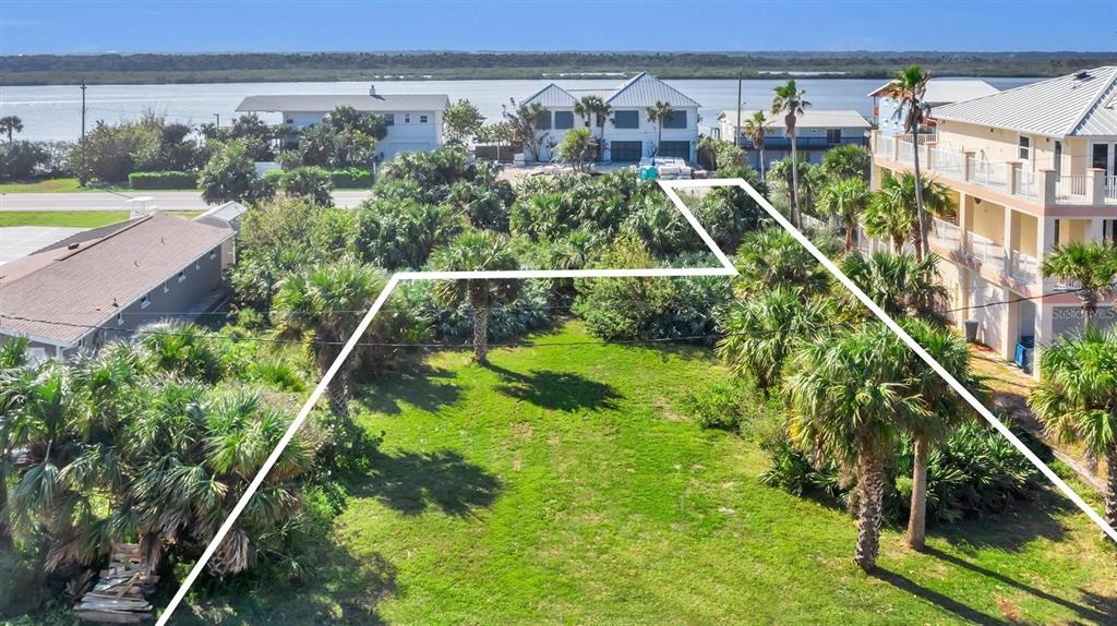 An aerial view shows a vacant, grassy lot outlined in white near a waterfront — 0 S ATLANTIC AVE, NEW SMYRNA BEACH, FL